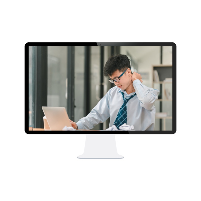 A young man looks stressed while working at his desk and rubbing his neck as he looks at his computer.