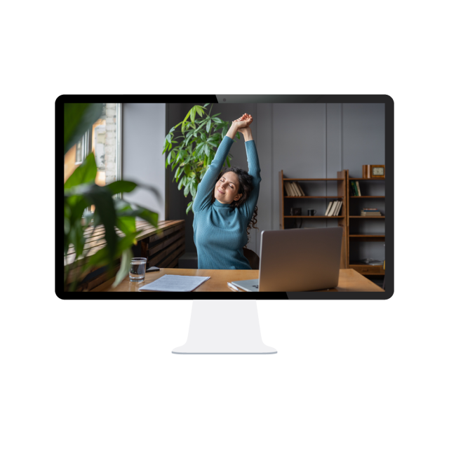 A computer monitor shows a relaxed employee stretching while seated at her desk with a computer in front of her. 